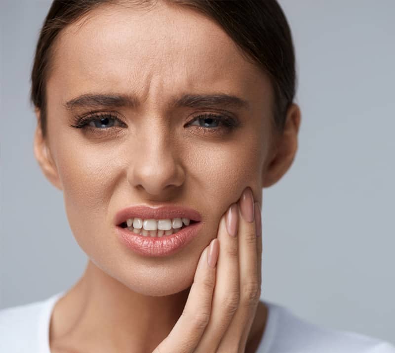 girl holding cheek with pain due to TMD