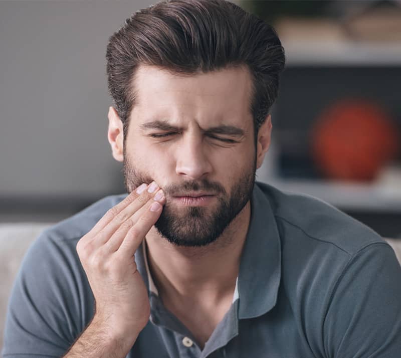 man with pain holding cheek